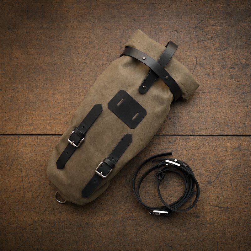 A single canvas bikepacking saddle bag laid flat on a wooden surface