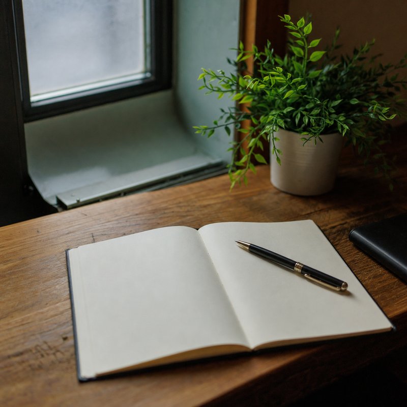 An open blank notebook with a pen resting across the page
